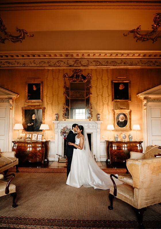 Bride and groom stand in beautiful, historical room